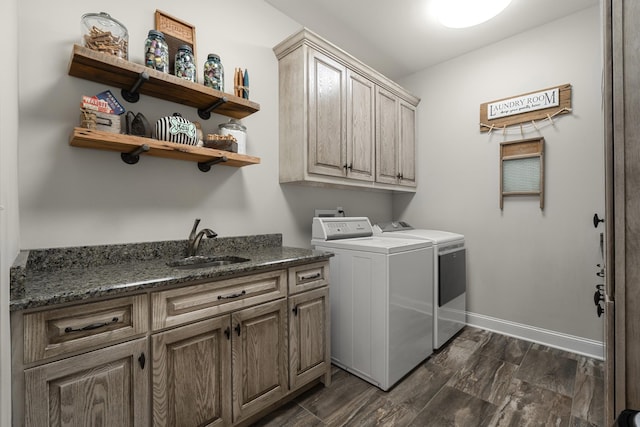 laundry room featuring cabinet space, baseboards, wood tiled floor, washer and dryer, and a sink