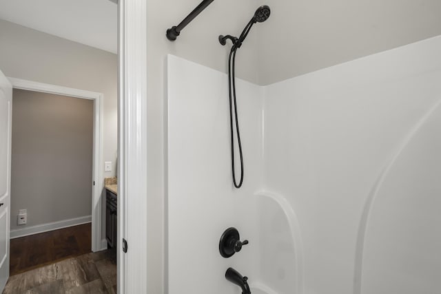 interior space with  shower combination, baseboards, wood finished floors, and vanity