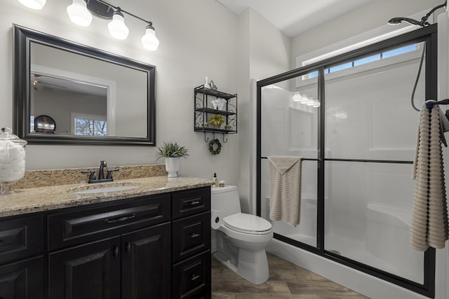 full bathroom featuring toilet, a stall shower, wood finished floors, and vanity