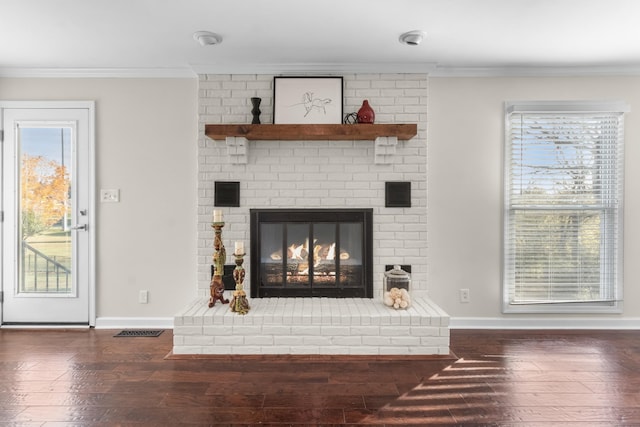 living room with dark wood-type flooring, ornamental molding, and a fireplace