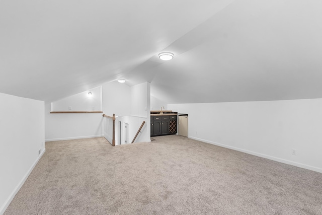 additional living space with vaulted ceiling, sink, and light colored carpet