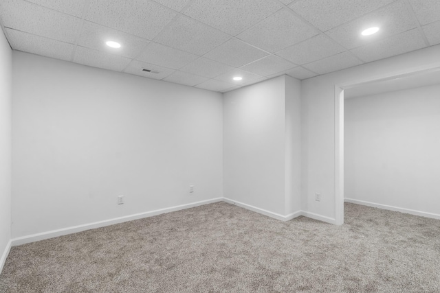 carpeted spare room with a drop ceiling