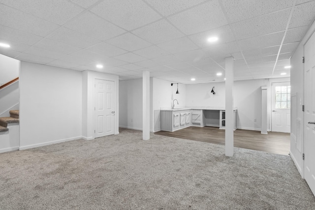 basement with a paneled ceiling, carpet flooring, and sink