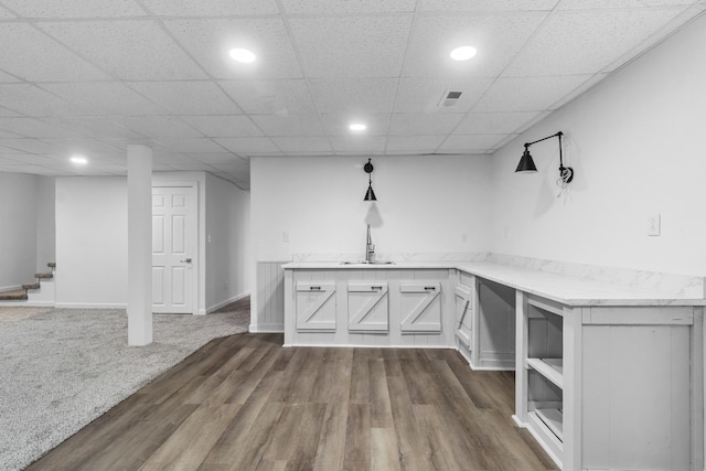 basement featuring a drop ceiling, sink, and dark colored carpet