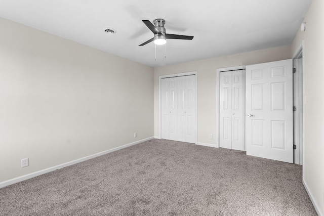 unfurnished bedroom with multiple closets, carpet, and ceiling fan