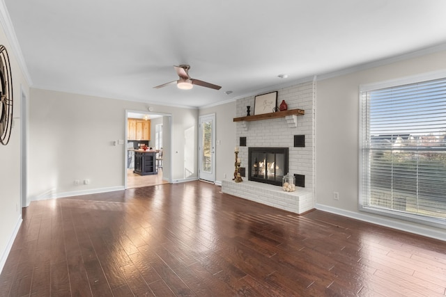 unfurnished living room featuring ornamental molding, ceiling fan, a fireplace, and dark hardwood / wood-style flooring