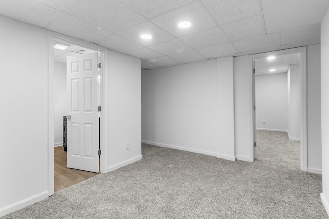 basement featuring light carpet and a paneled ceiling