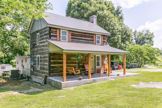 back of property with cooling unit, a porch, and a yard