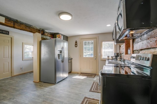 kitchen featuring stainless steel appliances, washer / dryer, sink, and light wood-type flooring