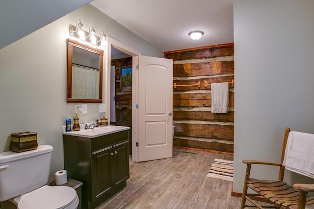 bathroom featuring toilet, wood walls, vanity, a shower with shower curtain, and hardwood / wood-style floors