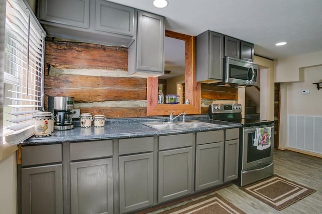 kitchen featuring stainless steel appliances, hardwood / wood-style flooring, sink, and gray cabinets