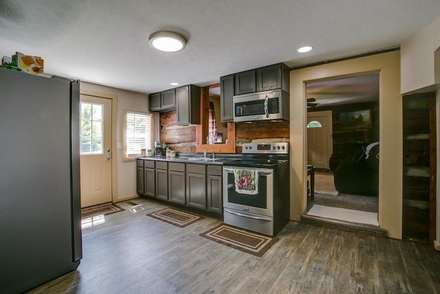 kitchen with dark hardwood / wood-style flooring, tasteful backsplash, and appliances with stainless steel finishes