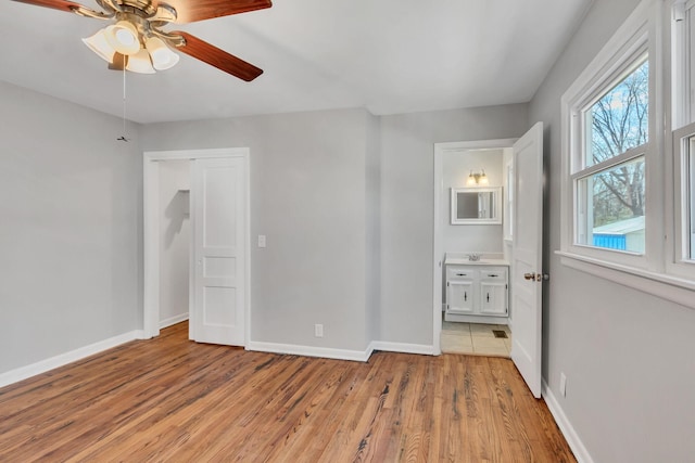 unfurnished bedroom featuring ceiling fan, light wood-type flooring, and ensuite bath