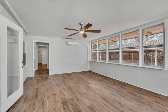 empty room with ceiling fan, hardwood / wood-style floors, and a wall unit AC