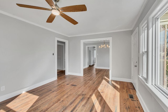 unfurnished room with an inviting chandelier, hardwood / wood-style floors, crown molding, and plenty of natural light