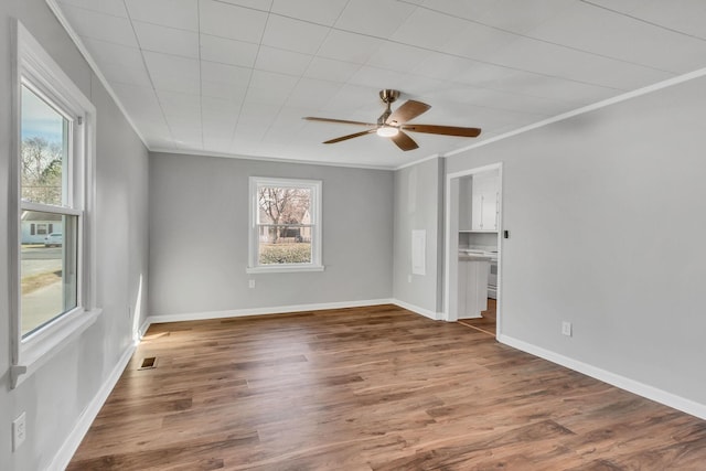 empty room with crown molding, plenty of natural light, and dark hardwood / wood-style flooring