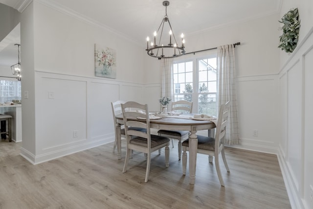 dining space with ornamental molding, light hardwood / wood-style flooring, and a notable chandelier