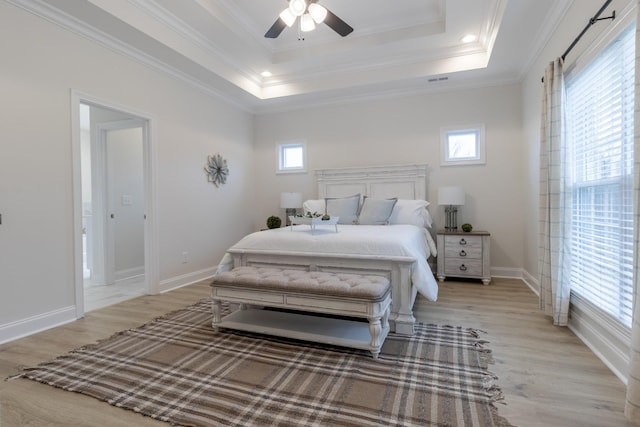 bedroom with ornamental molding, a tray ceiling, and light hardwood / wood-style floors