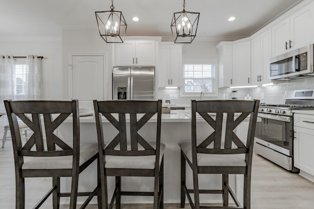 kitchen with white cabinetry, stainless steel appliances, and decorative light fixtures