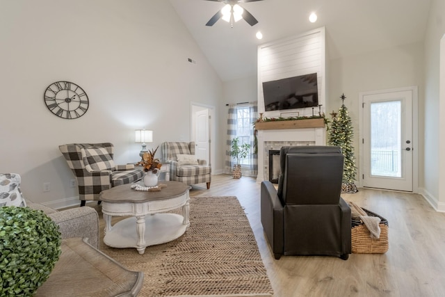 living room with ceiling fan, light wood-type flooring, and high vaulted ceiling