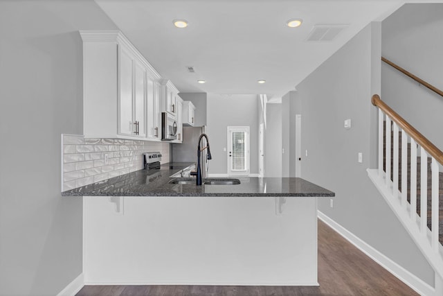 kitchen with a breakfast bar, stainless steel appliances, kitchen peninsula, and white cabinets