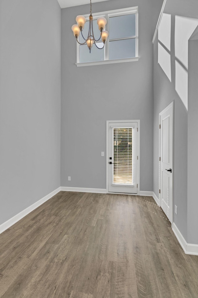 unfurnished living room featuring hardwood / wood-style flooring, a chandelier, and a high ceiling