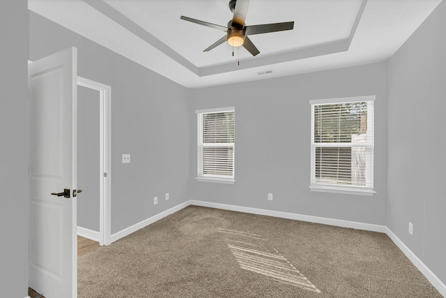 carpeted empty room featuring a raised ceiling and ceiling fan