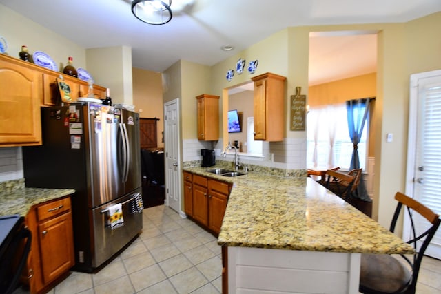 kitchen featuring tasteful backsplash, stainless steel fridge, range, and sink