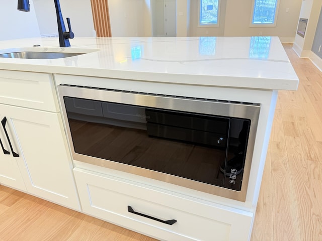 details with built in microwave, sink, light hardwood / wood-style flooring, and white cabinets