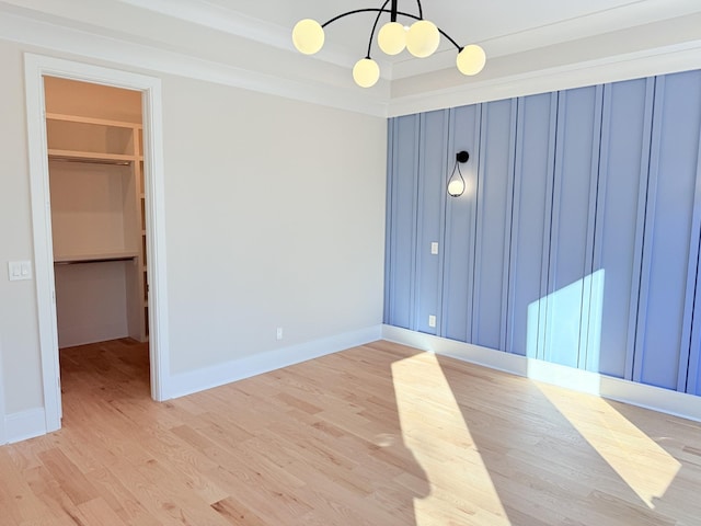 spare room featuring a notable chandelier, light hardwood / wood-style floors, and a tray ceiling