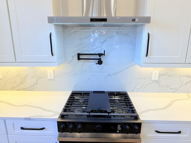 details with white cabinetry, light stone countertops, gas stove, island exhaust hood, and decorative backsplash