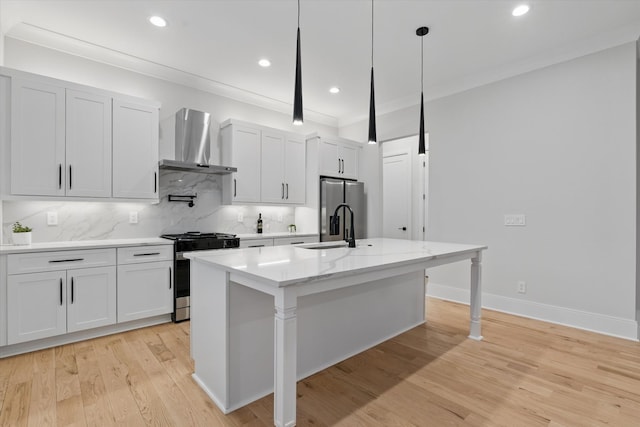 kitchen with a center island with sink, stainless steel appliances, ornamental molding, a sink, and wall chimney exhaust hood