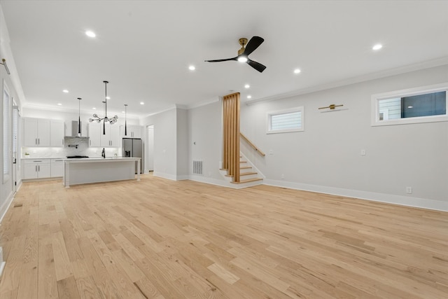 unfurnished living room featuring light wood finished floors, visible vents, stairway, crown molding, and recessed lighting