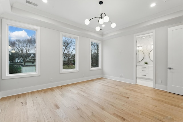 interior space with a tray ceiling, visible vents, a chandelier, light wood-type flooring, and baseboards