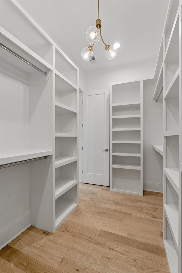 spacious closet featuring an inviting chandelier, visible vents, and wood finished floors