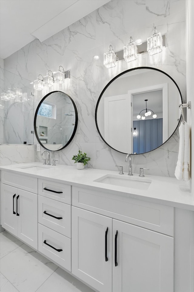 full bathroom featuring stone wall, marble finish floor, a sink, and double vanity