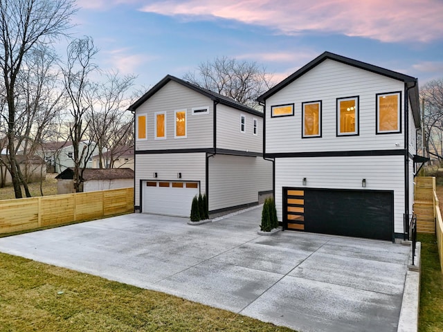 view of front of house featuring a garage, concrete driveway, and fence