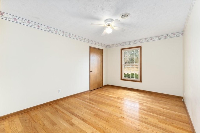 unfurnished room with ceiling fan, a textured ceiling, and light wood-type flooring