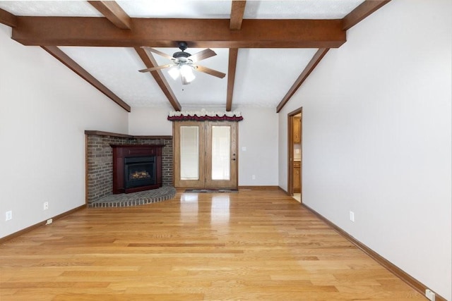 unfurnished living room featuring a brick fireplace, lofted ceiling with beams, ceiling fan, and light wood-type flooring