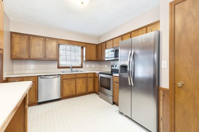 kitchen with sink, stainless steel appliances, and a textured ceiling