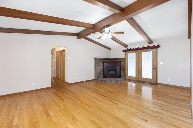 unfurnished living room featuring lofted ceiling with beams, ceiling fan, a fireplace, and light hardwood / wood-style floors