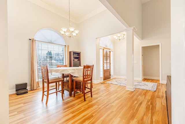 dining space featuring an inviting chandelier, a towering ceiling, and wood-type flooring