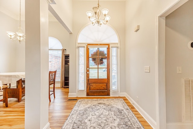 entrance foyer with light hardwood / wood-style flooring, a chandelier, and a high ceiling