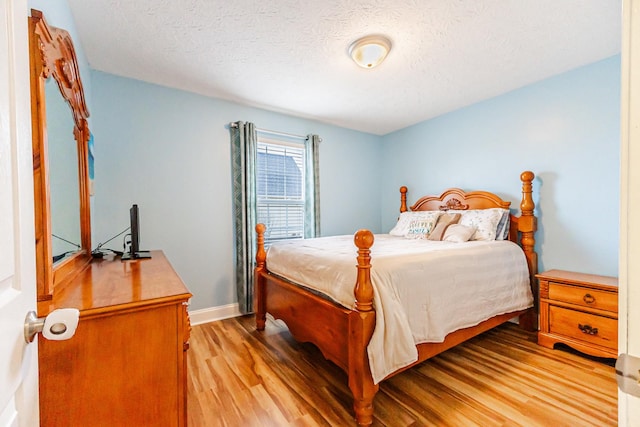 bedroom featuring light hardwood / wood-style flooring and a textured ceiling