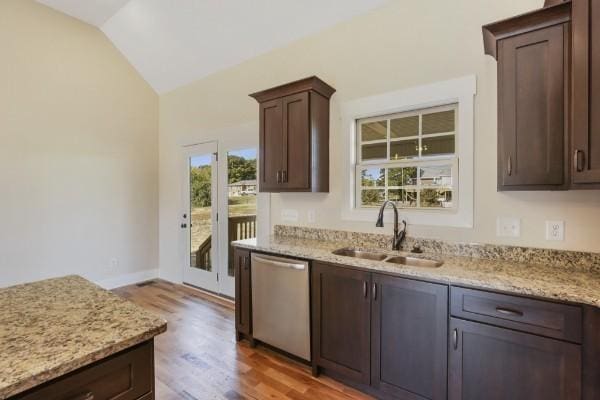 kitchen with sink, dishwasher, light stone counters, dark brown cabinetry, and vaulted ceiling