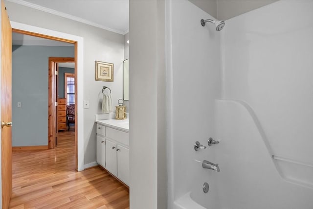 bathroom featuring bathing tub / shower combination, ornamental molding, hardwood / wood-style floors, and vanity