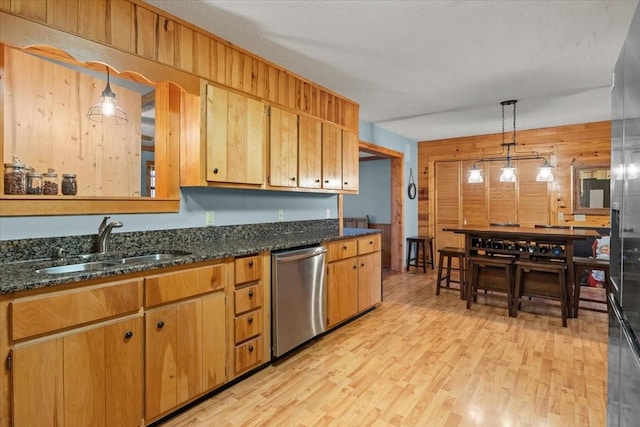 kitchen with sink, hanging light fixtures, light wood-type flooring, wooden walls, and dishwasher