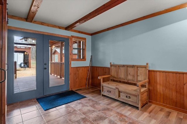 entryway with wooden walls, beam ceiling, and french doors