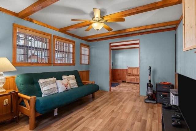 living area with beam ceiling, ceiling fan, and light wood-type flooring