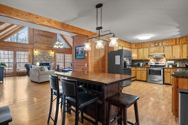 kitchen with black fridge, electric range, wooden walls, pendant lighting, and a fireplace